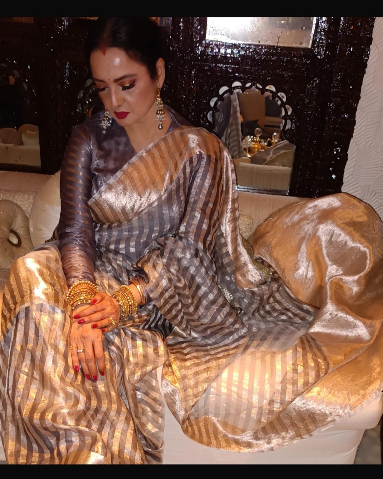 Rekha exudes her signature regal charm, wearing a stunning custom-made handloom strip tissue saree by Manish Malhotra. 